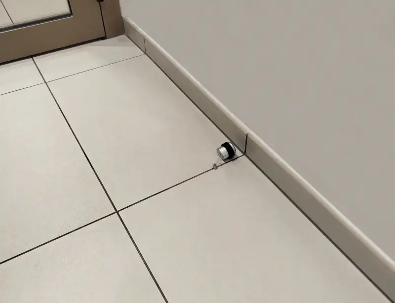 Butée de porte au sol cassée sur carrelage.