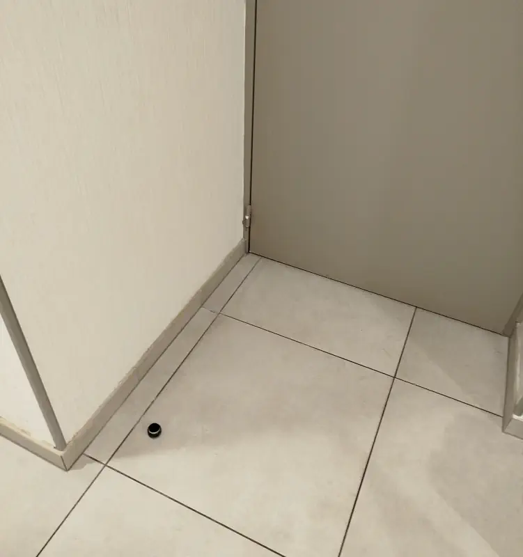 Une butée de porte solidement refixée sur du carrelage.